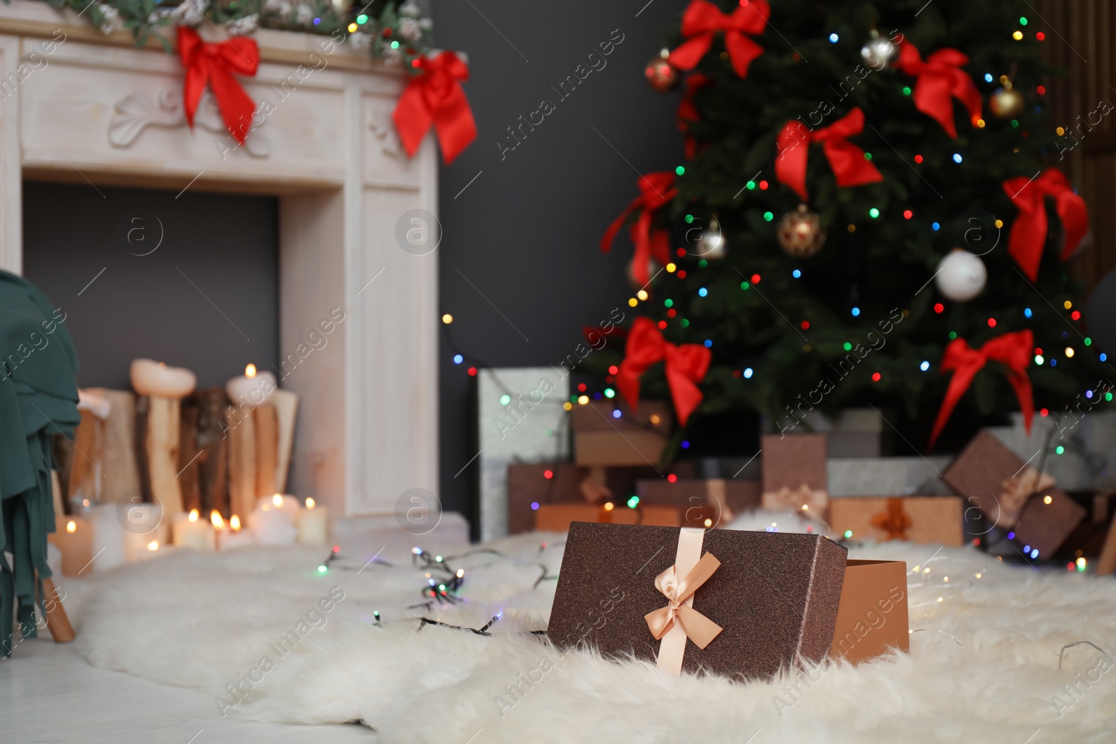 Photo of Gift box on fur rug and Christmas tree in stylish living room interior