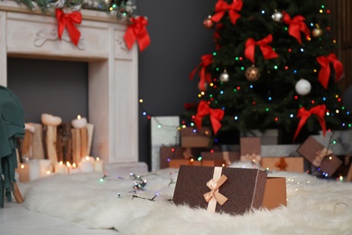 Photo of Gift box on fur rug and Christmas tree in stylish living room interior