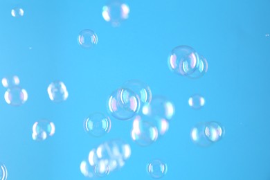 Photo of Beautiful transparent soap bubbles on light blue background