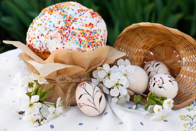 Photo of Eggs with floral ornaments and kulich for Easter near blossoming tree twigs on cloth