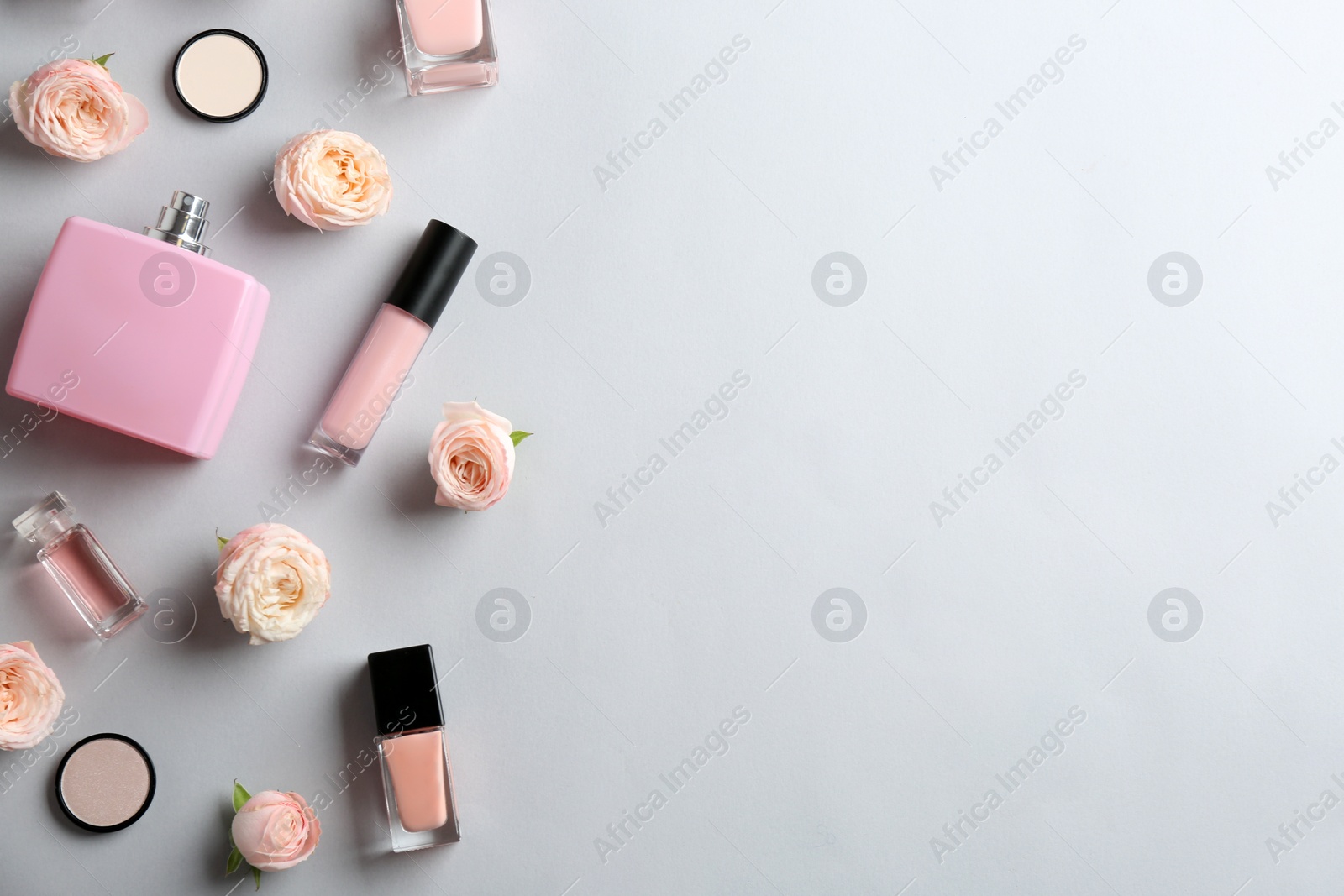 Photo of Flat lay composition with bottles of perfume, cosmetics and roses on grey background. Space for text