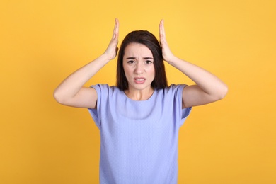 Photo of Portrait of stressed young woman on yellow background