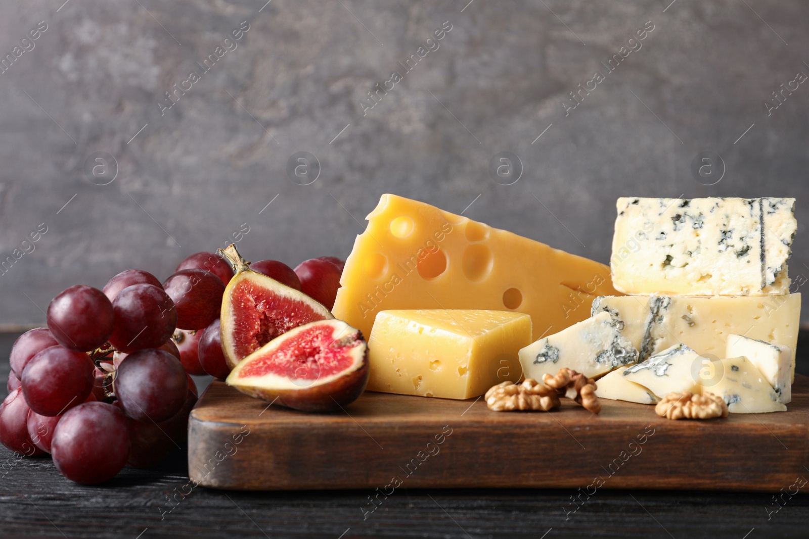 Photo of Different delicious cheeses served on wooden board