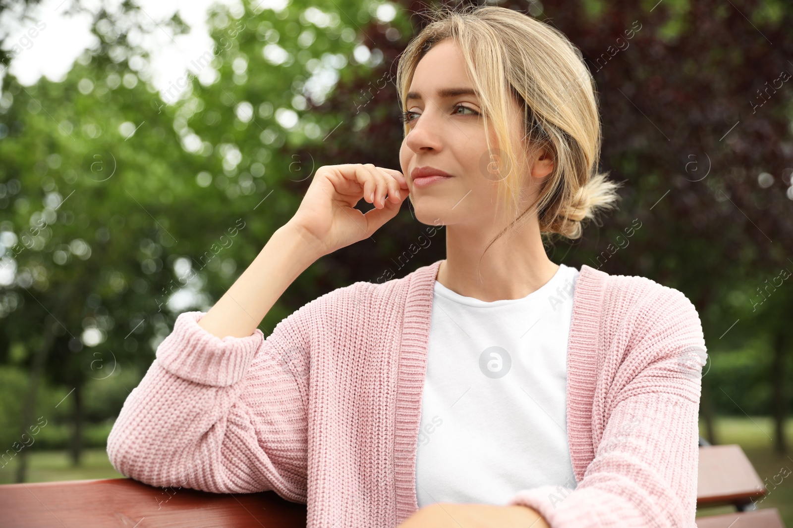 Photo of Beautiful young woman sitting on bench in park