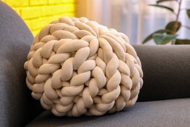 Soft knitted pillow on sofa indoors, closeup