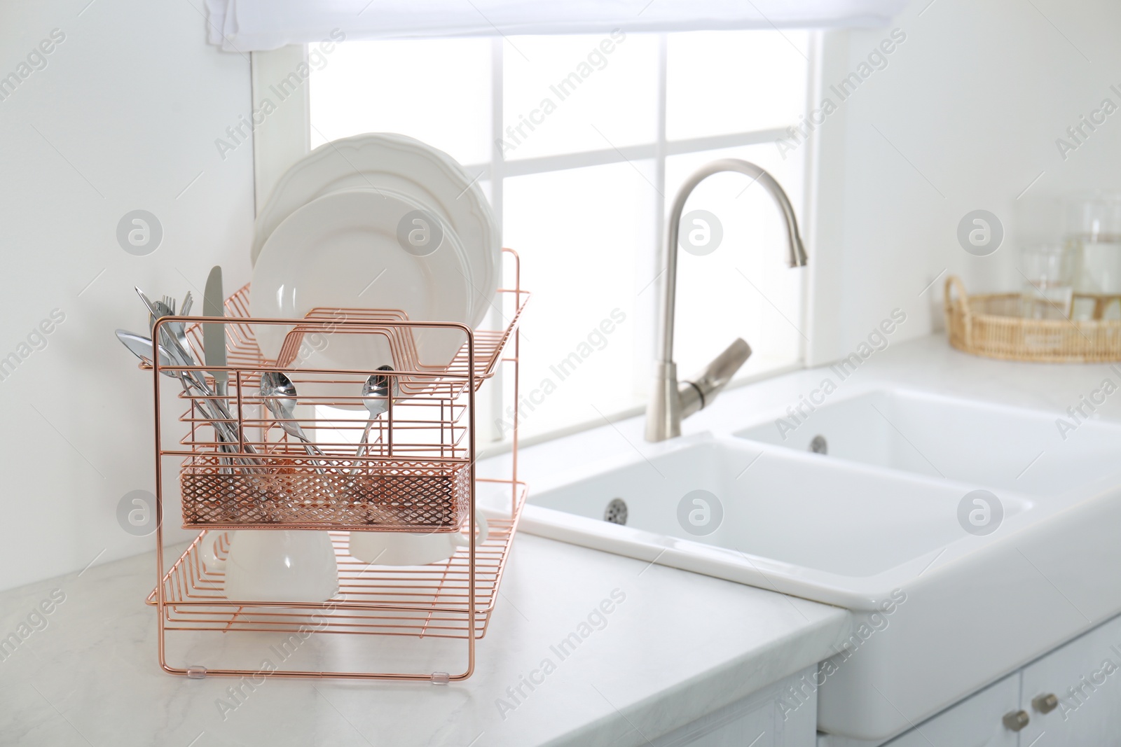 Photo of Clean dishes on drying rack in modern kitchen interior