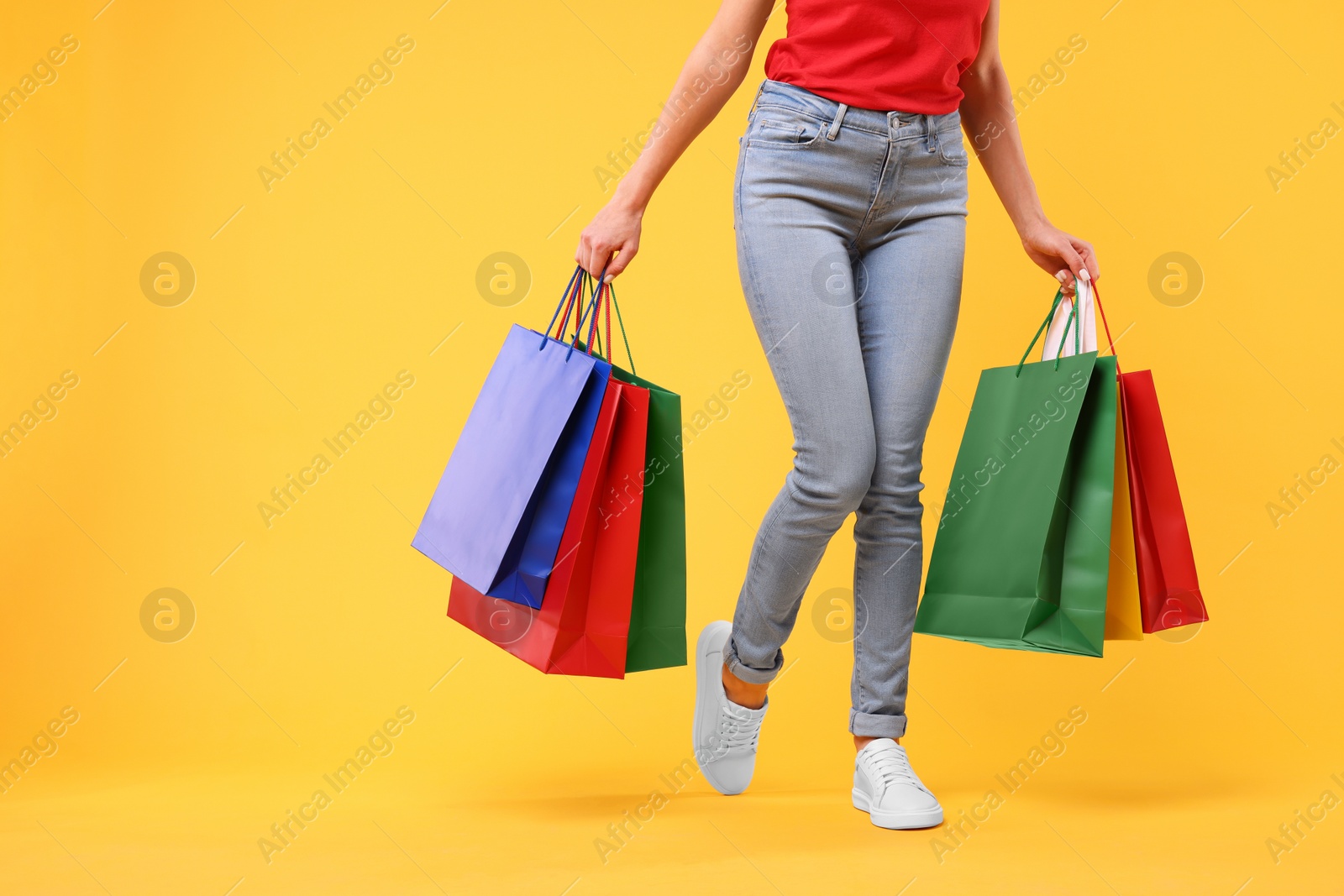 Photo of Woman with shopping bags on yellow background, closeup