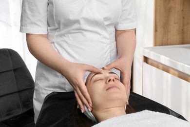 Photo of Cosmetologist making face massage to client in clinic, closeup