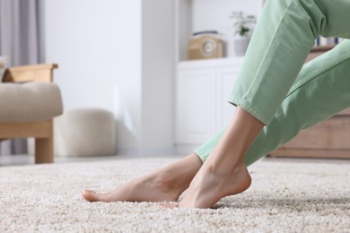 Woman on soft light brown carpet at home, closeup. Space for text