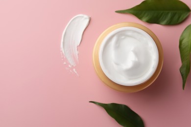 Jar of face cream, sample and fresh leaves on pink background, flat lay. Space for text