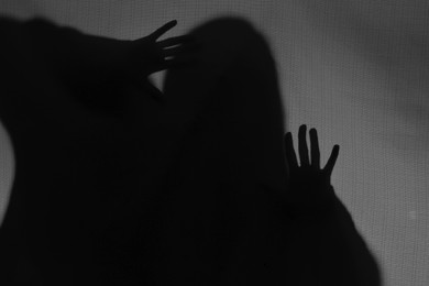 Silhouette of creepy ghost behind grey cloth