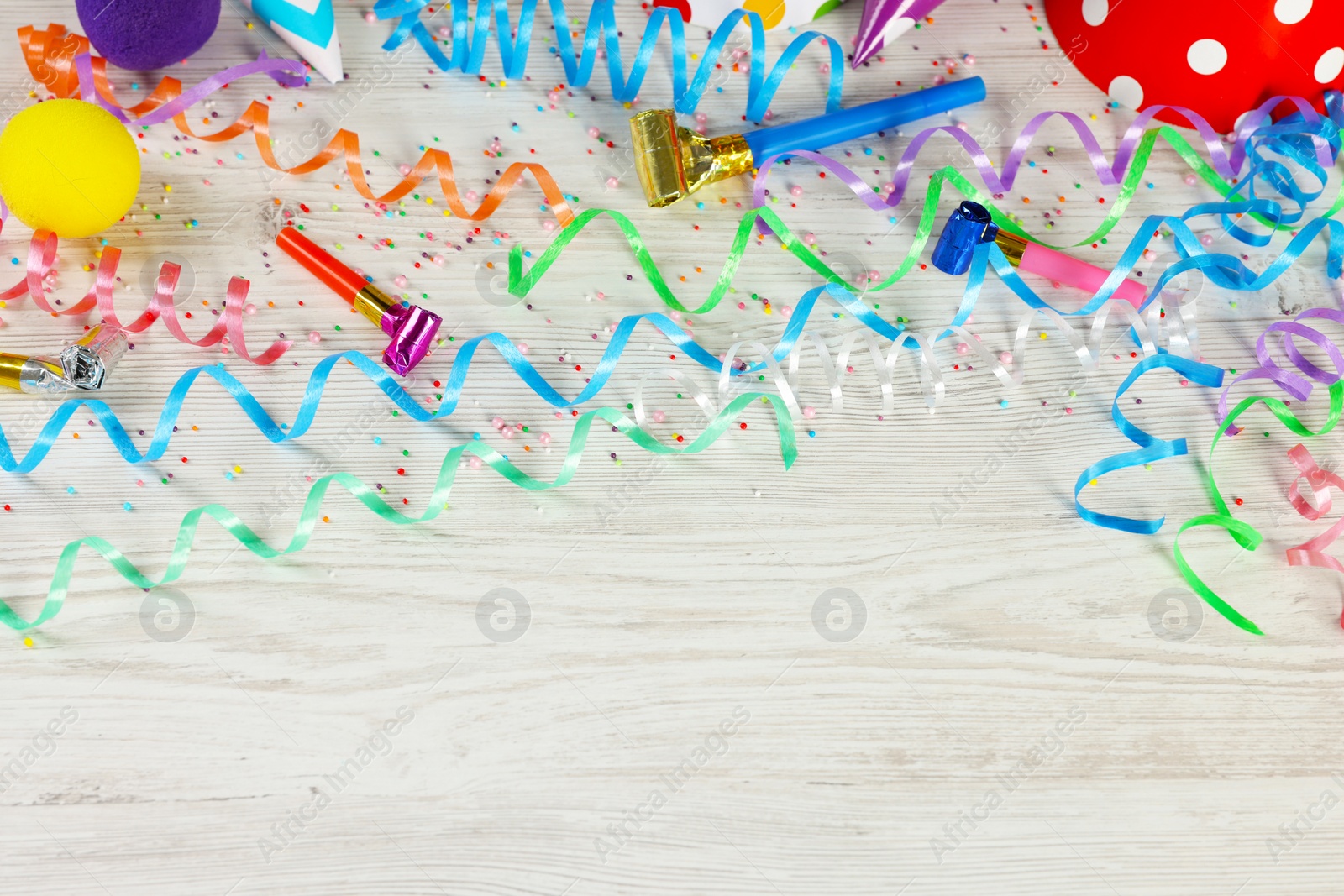 Photo of Flat lay composition with colorful serpentine streamers and other party accessories on white wooden table, space for text