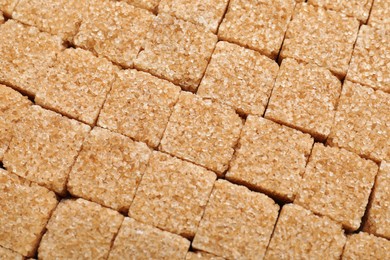 Brown sugar cubes as background, top view