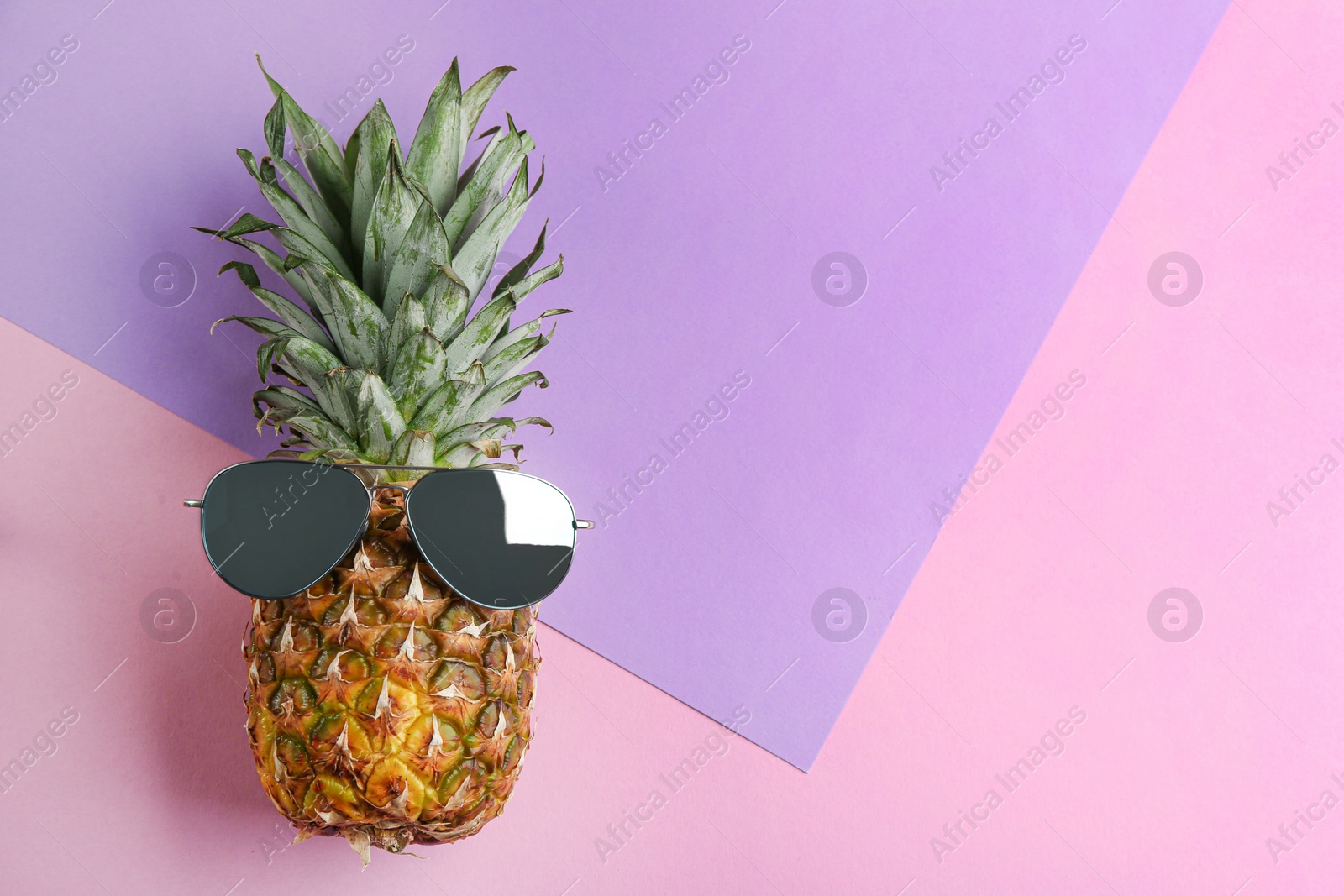 Photo of Funny face made of pineapple and sunglasses on color background, top view with space for text. Vacation time