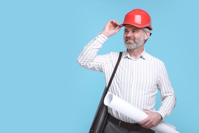 Photo of Architect in hard hat holding draft on light blue background. Space for text
