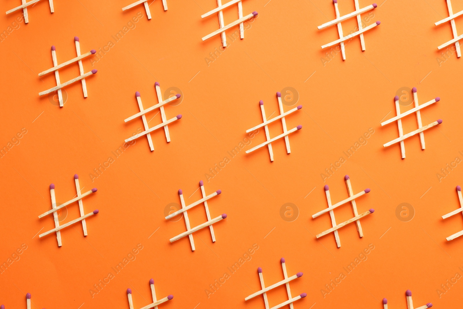 Photo of Hashtag symbols made of wooden matches on orange background, flat lay