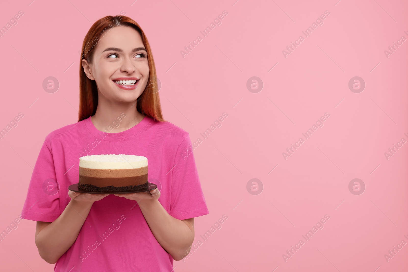 Photo of Young woman with tasty cake on pink background, space for text