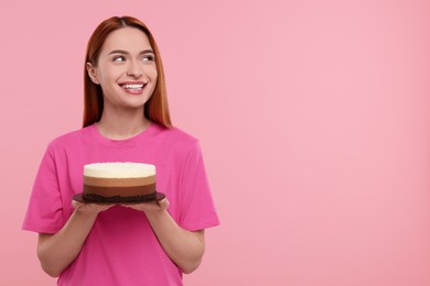 Young woman with tasty cake on pink background, space for text
