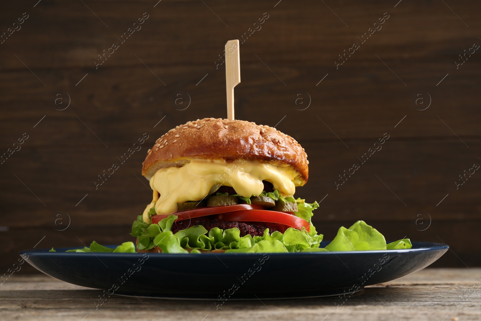 Photo of Delicious vegetarian burger served on wooden table