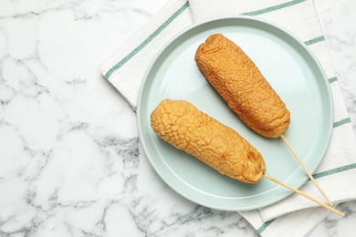 Photo of Delicious deep fried corn dogs on white marble table, flat lay. Space for text