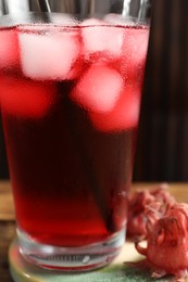 Photo of Glass of delicious iced hibiscus tea on table, closeup