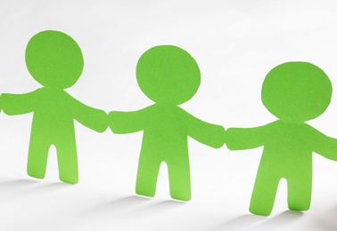 Photo of Paper people holding hands on light background. Unity concept