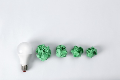 Photo of Composition with lamp bulb, crumpled paper balls and space for text on white background, top view. Creative concept