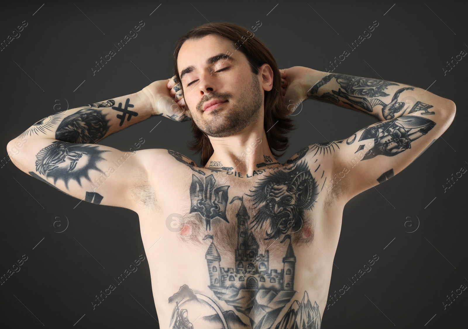 Photo of Young man with tattoos on body against black background