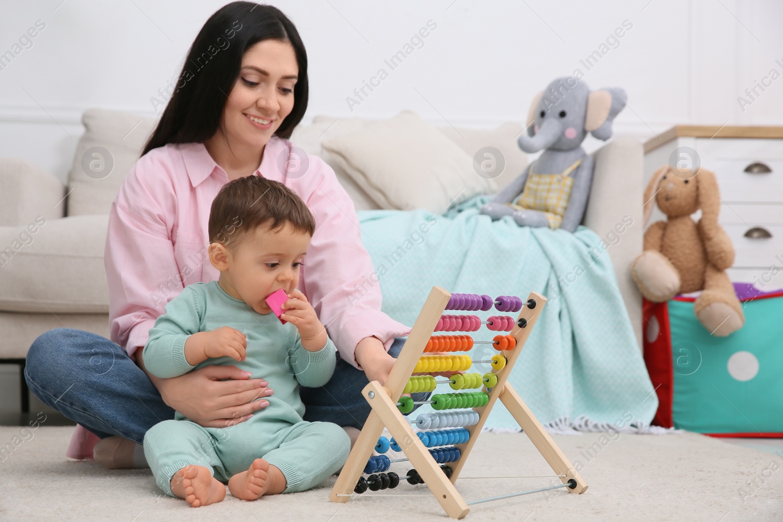 Photo of Cute baby boy with mother and abacus on floor at home
