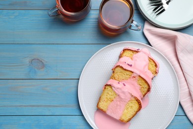 Photo of Delicious cake with pink glaze served on light blue wooden table, flat lay. Space for text