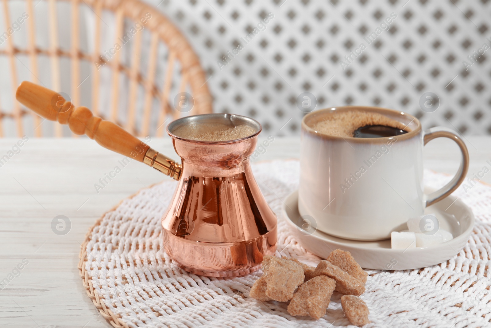 Photo of Turkish coffee. Cezve and cup with hot aromatic coffee and sugar on white wooden table