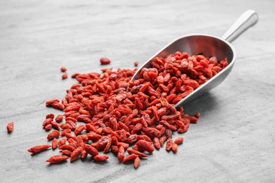 Photo of Scoop and dried goji berries on grey table. Healthy superfood