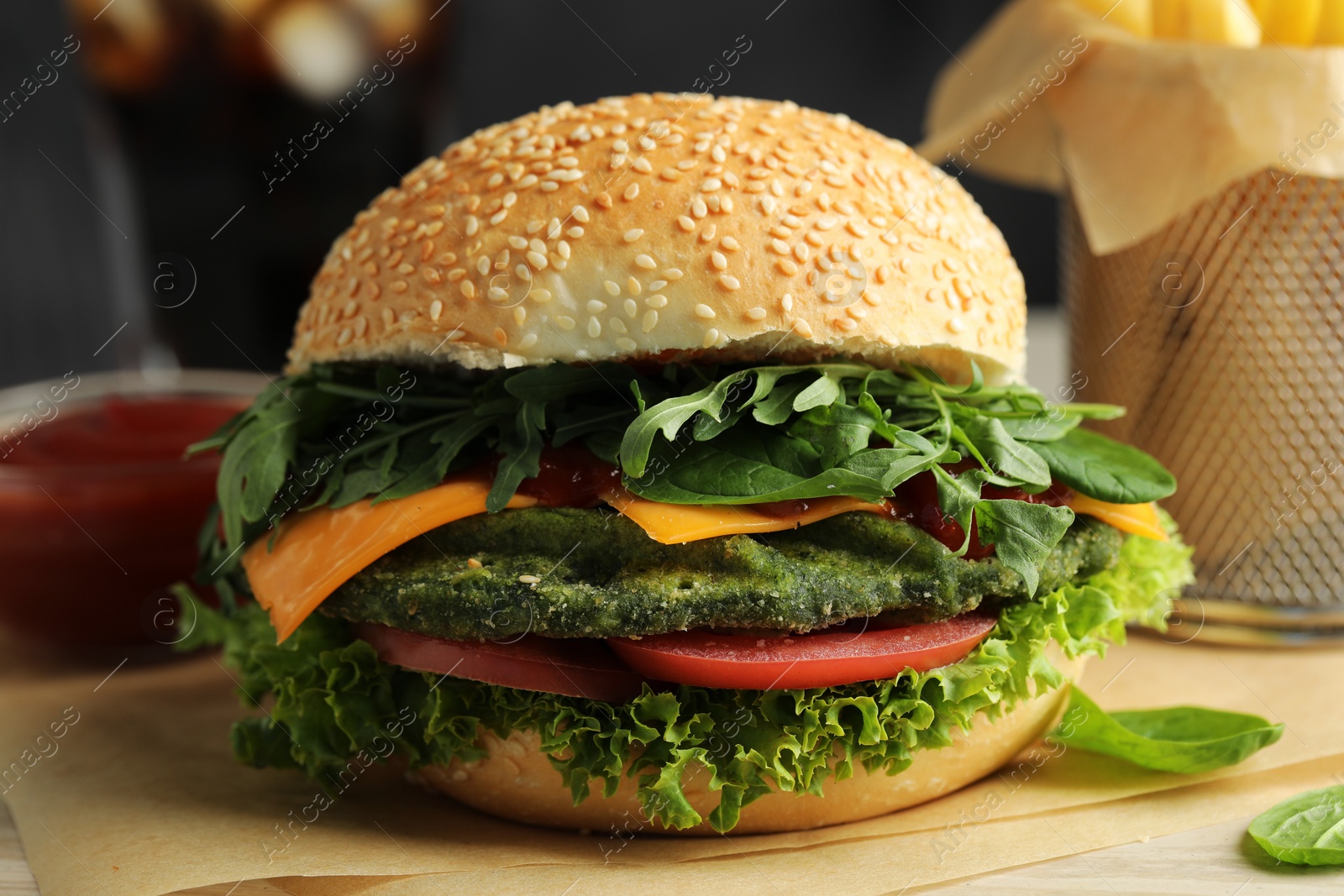 Photo of Tasty vegetarian burger with spinach cutlet, cheese and vegetables served on white table, closeup