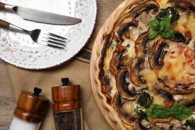 Photo of Delicious quiche with mushrooms and basil served on wooden table, flat lay