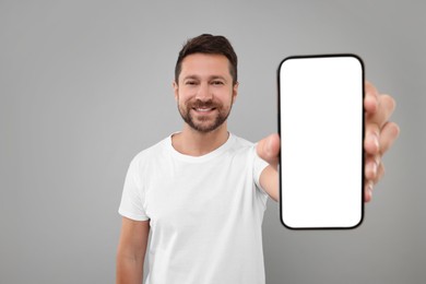 Handsome man showing smartphone in hand on light grey background