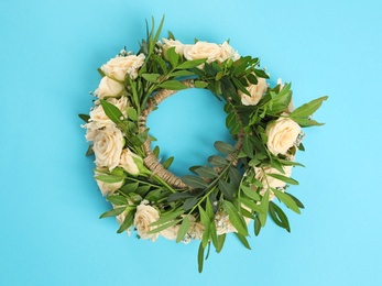 Wreath made of beautiful flowers on light blue background, top view