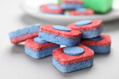 Photo of Many dishwasher detergent tablets on light background, closeup