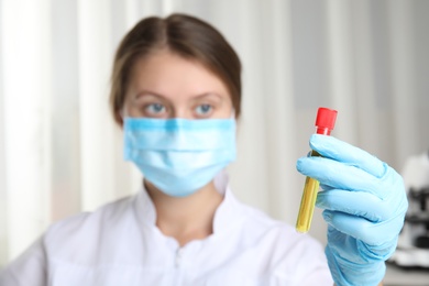 Photo of Doctor holding test tube with urine sample for analysis in laboratory, focus on hand