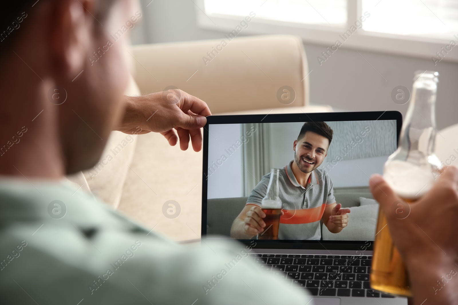 Photo of Friends drinking beer while communicating through online video conference at home. Social distancing during coronavirus pandemic