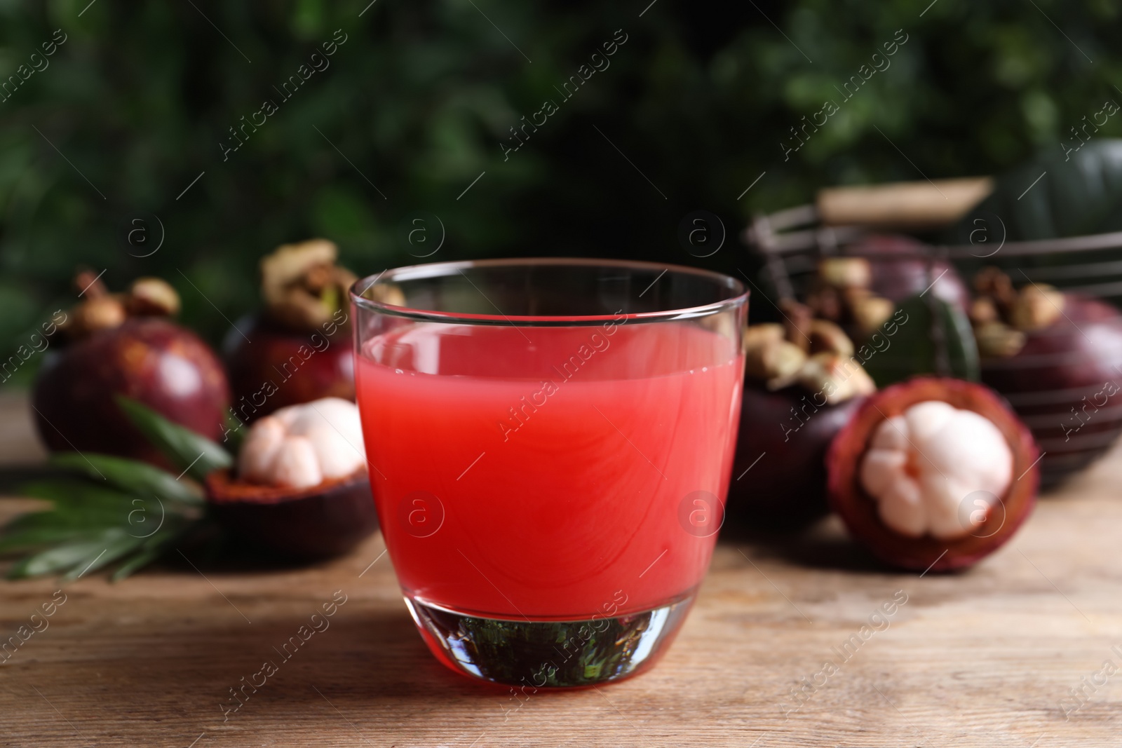 Photo of Delicious mangosteen juice in glass on wooden table