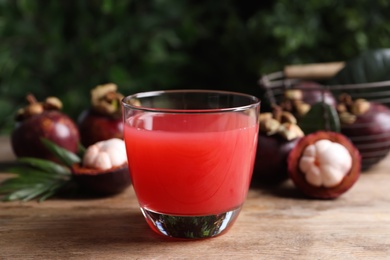 Delicious mangosteen juice in glass on wooden table