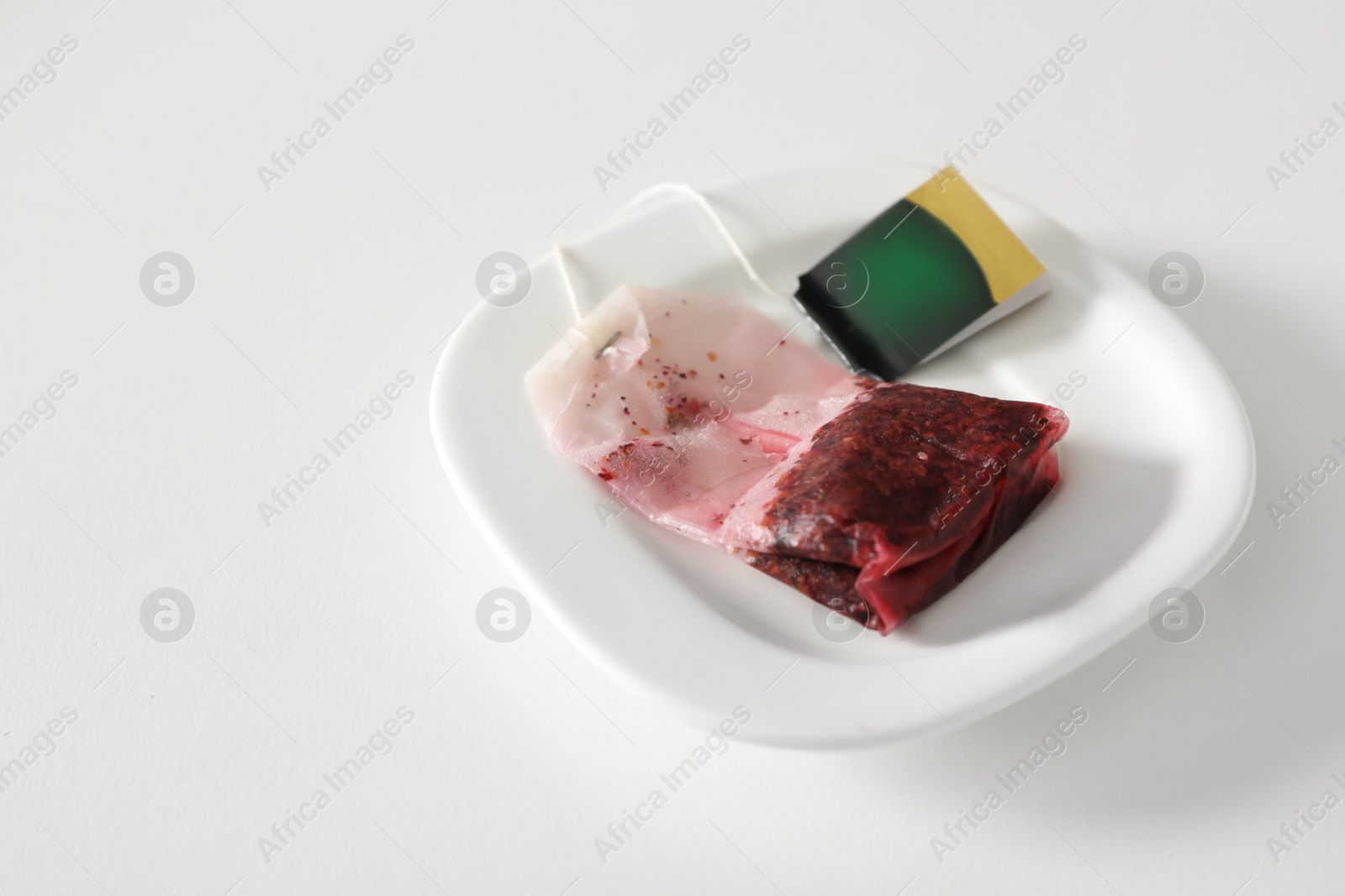 Photo of Saucer with used tea bag on white table