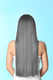 Image of Woman with gray hair on light blue background, back view