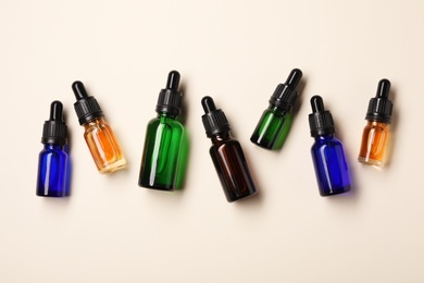 Photo of Flat lay composition with cosmetic bottles of essential oils on color background