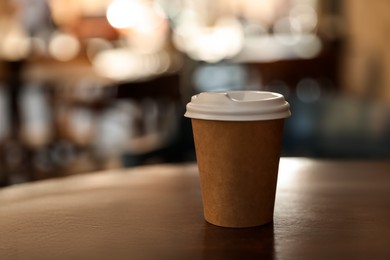 Photo of Cardboard takeaway coffee cup with plastic lid on table in outdoor cafe, space for text