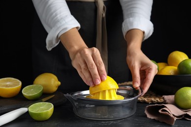 Photo of Woman squeezing lemon juice at black table, closeup