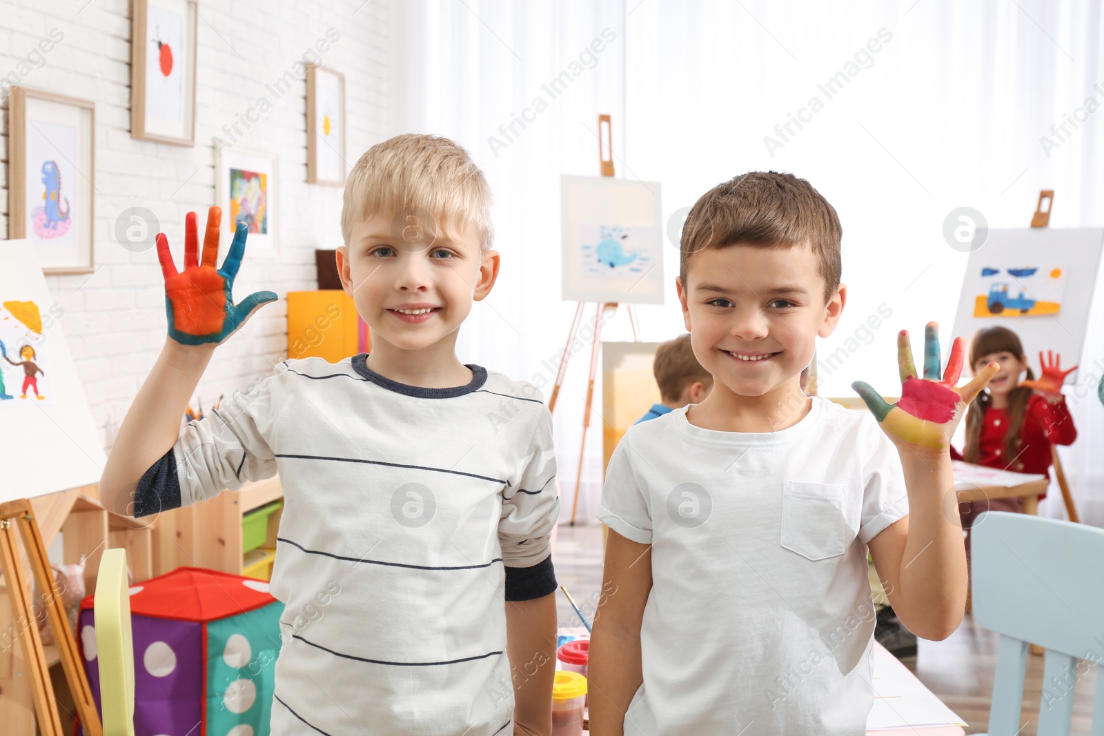 Photo of Cute little children with painted palms in room