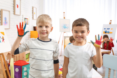 Photo of Cute little children with painted palms in room