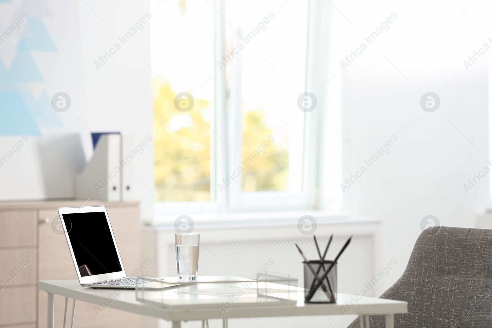 Photo of Laptop and stationery on white table in office. Modern workplace