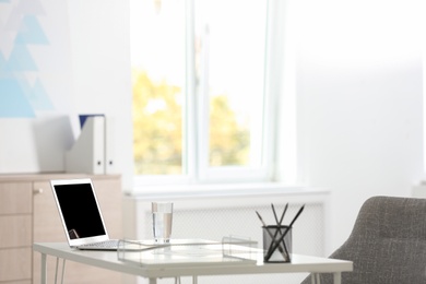 Laptop and stationery on white table in office. Modern workplace